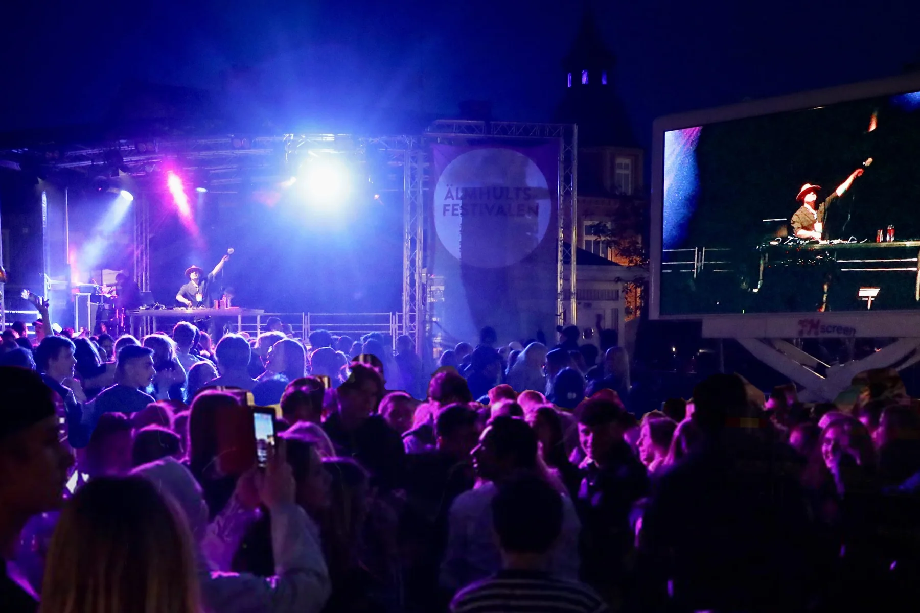 Festival crowd watching DJ Ale on stage under blue and purple lights