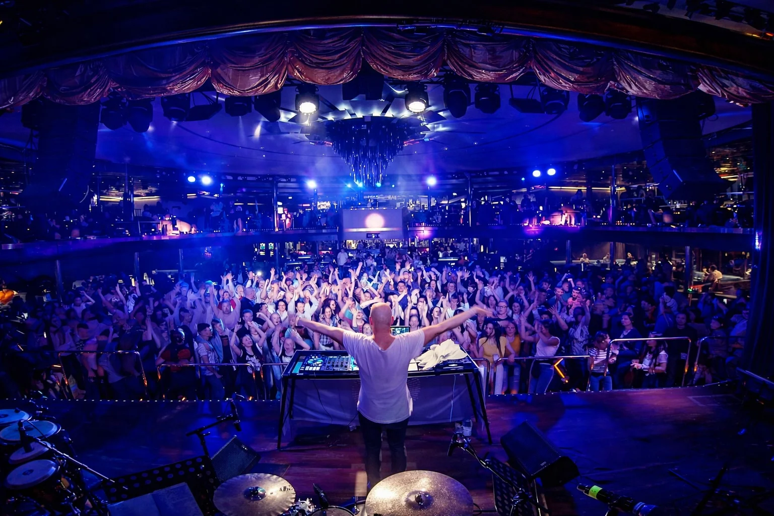 DJ Ale with arms raised in front of a cheering crowd