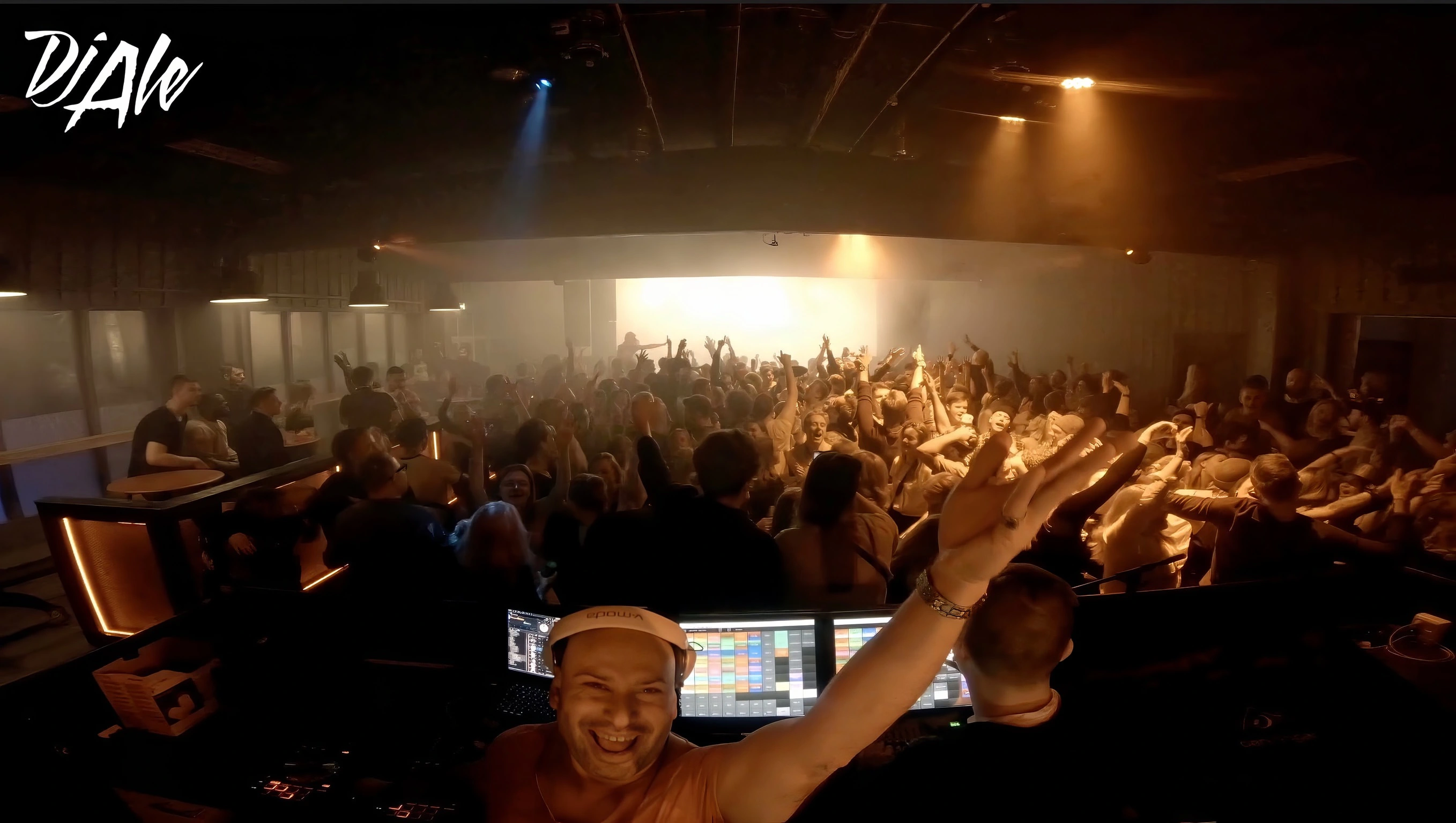 DJ Ale raising one hand above the decks with a packed dance floor in Vemdalen
